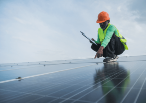 Worker with hard hat and high visibility clothing inspecting a solar panel in Lesotho, Africa